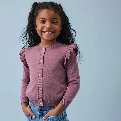 Roze vest met ruches op de schouders en blauwe jeans.
