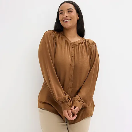 Bruine blouse met knopen en rimpeleffect bij de hals.