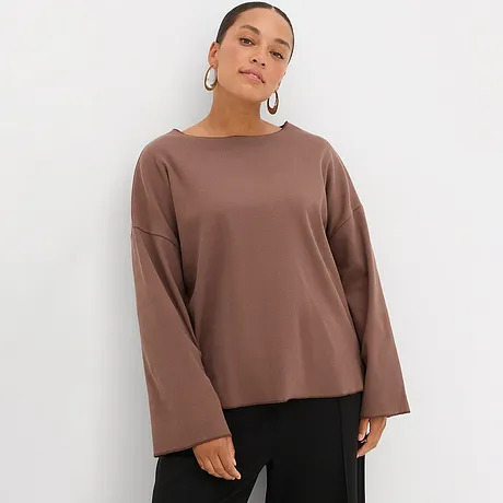 Bruine longsleeve met wijde mouwen, gecombineerd met zwarte broek.