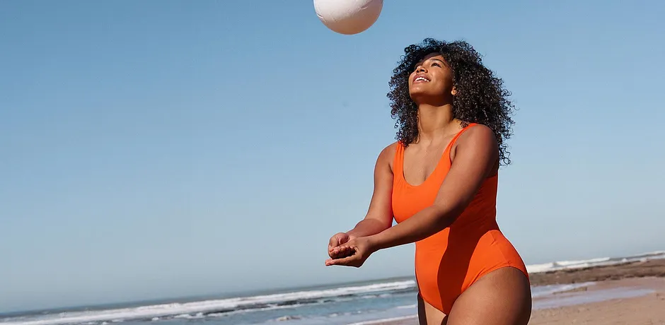 Fel oranje badpak op het strand. Sportieve elegantie onder een stralend blauwe lucht.