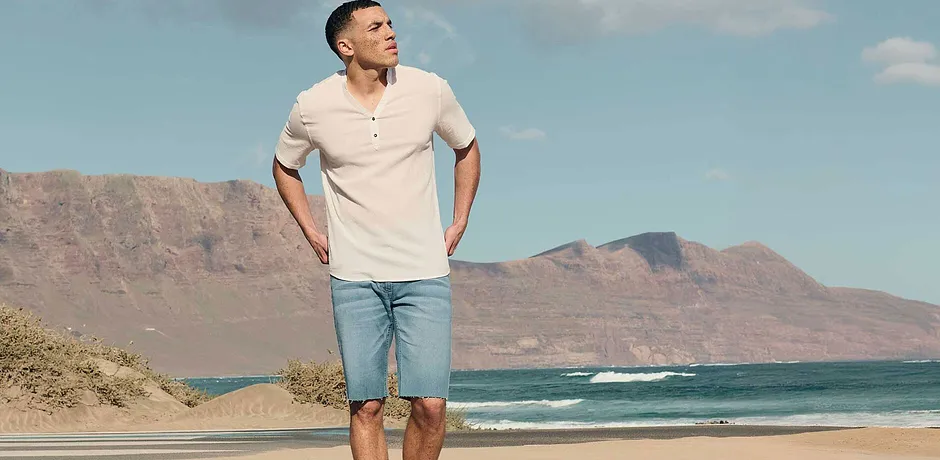 Zomerse look: Lichtgekleurde korte mouwen Henley-shirt en lichtblauwe jeansshorts.