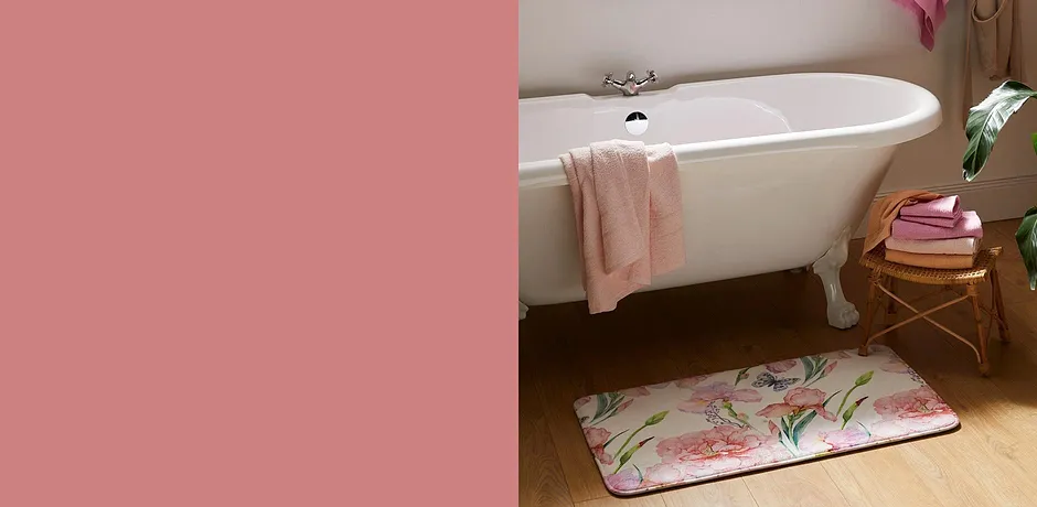 Frisse handdoeken en een gebloemde badmat versieren de badkamer met een witte vintage badkuip.