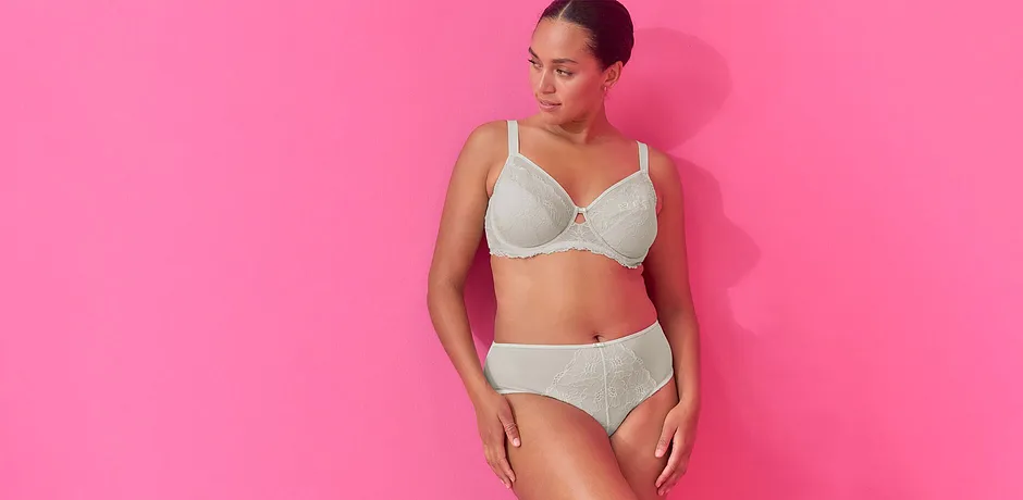 Elegante weiße Unterwäsche mit Spitzendetails. Figurbetonter BH und passender Slip auf leuchtendem rosa Hintergrund.