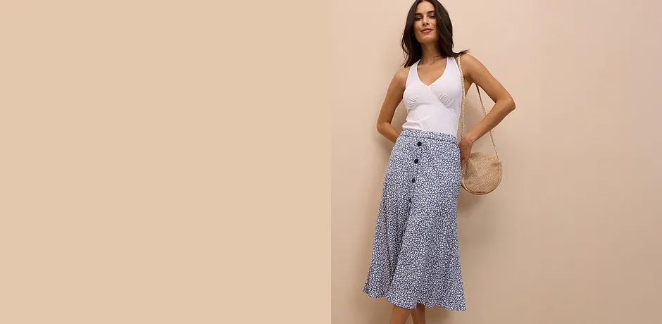 Mouwloze witte top en een gedessineerde midi rok. Echt chic voor de zomer is de combinatie met de rieten tas.