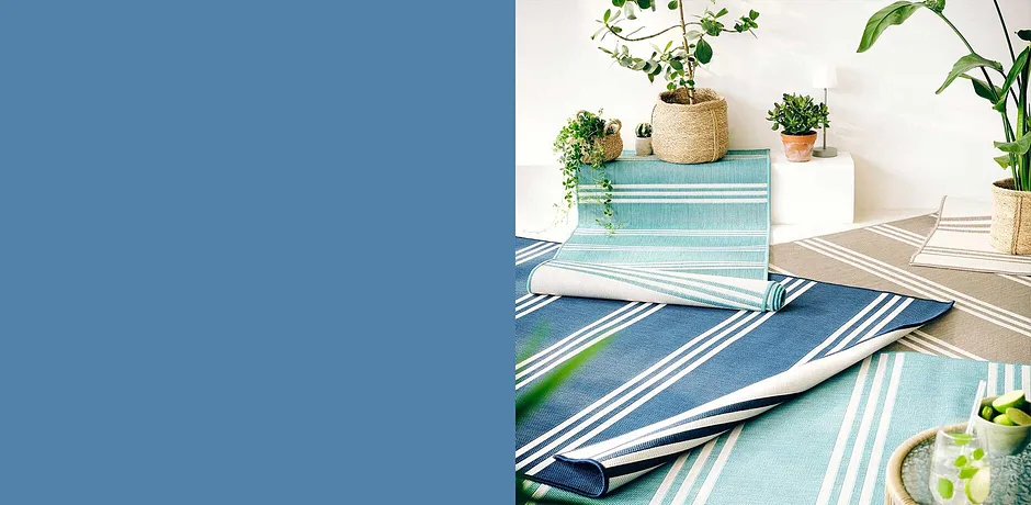 Gestreept kleed in blauw- en grijstinten voor de tuintafel, omgeven door echte planten.