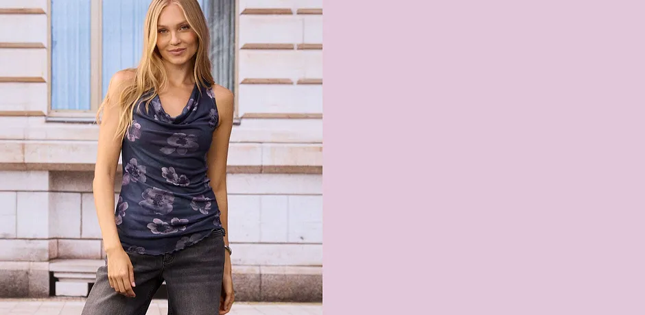 Top met romantische bloemenprint en watervalhals op grijze jeans.