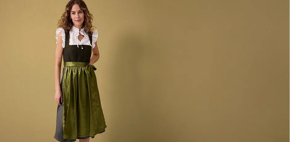 Een traditioneel dirndl met witte blouse, zwart lijfje en groene rok wordt gepresenteerd.