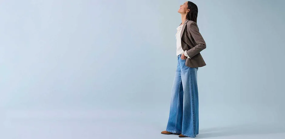 Wijde jeans, licht topje en beige blazer voor een ontspannen stijl.