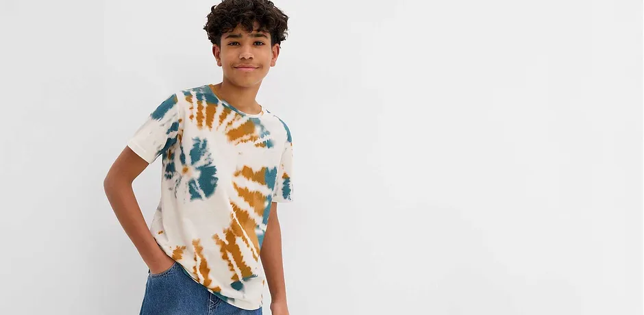 Modern tie-dye T-shirt in blauw en oranje, gecombineerd met klassieke jeans voor een casual look.