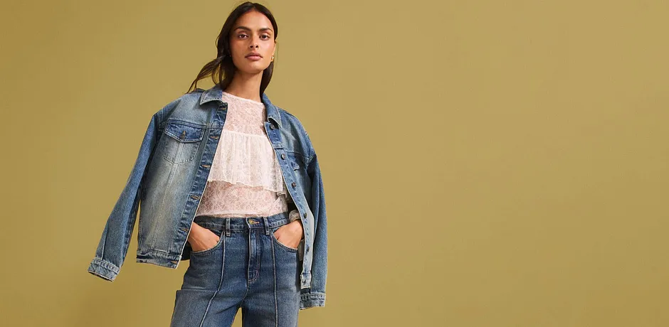 Casual denimlook met een spijkerjack, lichte kanten blouse en high-waist jeans voor een moderne stijl.