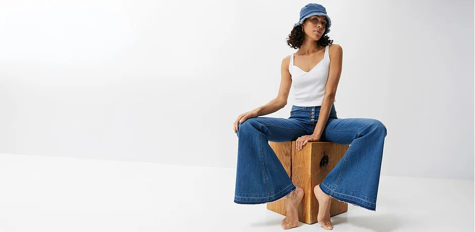 Wijde jeans, wit topje en blauwe pet: casual zomerlook voor warme dagen.
