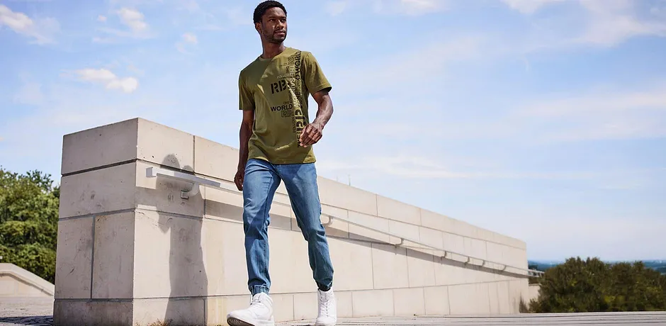 Casual look met een olijfgroen T-shirt en lichtblauwe jeans. 