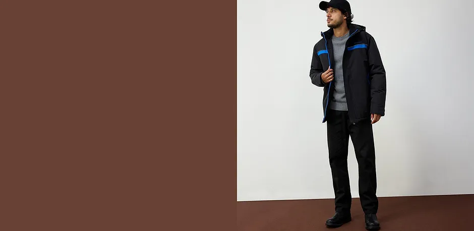 Sportieve winterjas in zwart met blauwe accenten, gecombineerd met grijs shirt en zwarte broek.