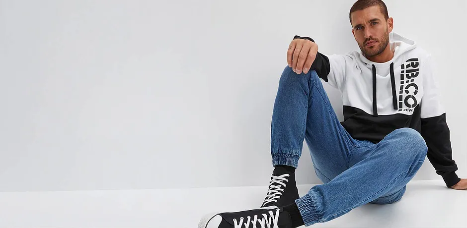 Casual look met jeans, tweekleurige hoodie en hoge sneakers.