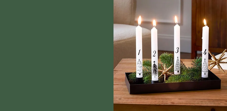 Vier witte adventskaarsen branden op een donkere kaarsenhouder.