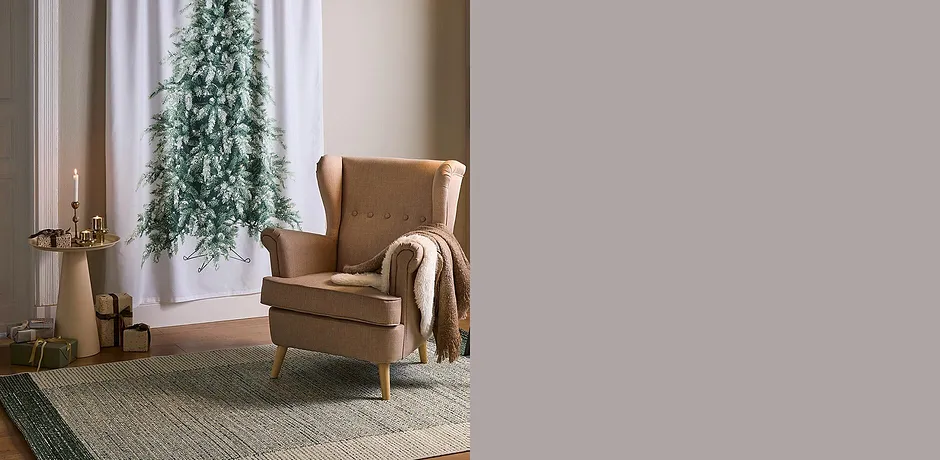 Comfortabele fauteuil met wollen deken. Het vloerkleed en de kaarsen zorgen voor een warme sfeer.