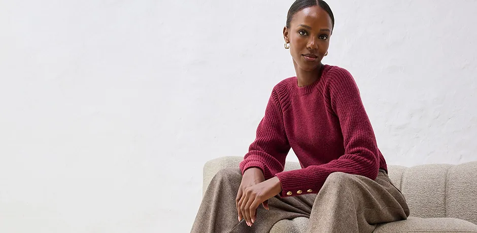 Rode trui met beige broek op lichte bank.