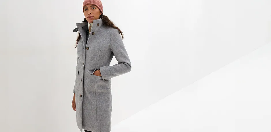 Elegante lange wollen jas in grijs met bruine muts en sjaal.