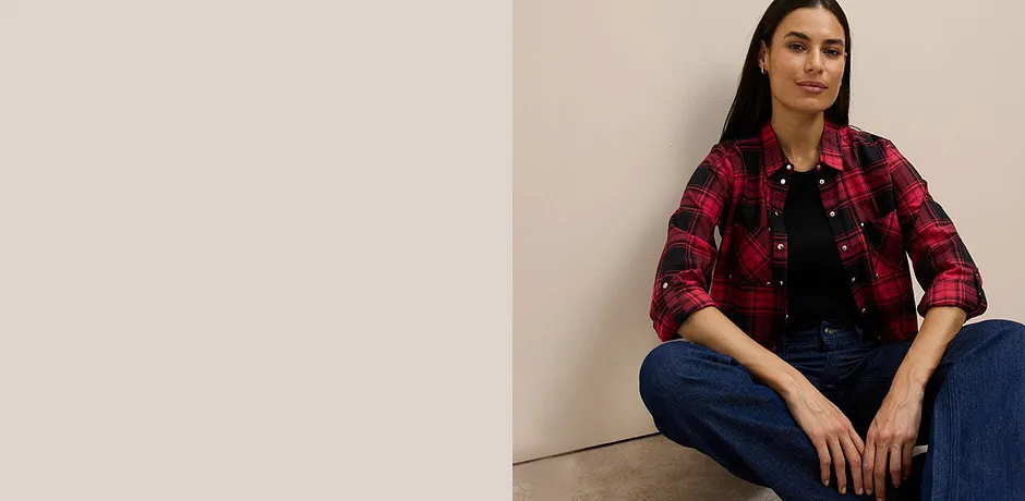 Rood-zwart geruite overhemdblouse over zwarte top gecombineerd met klassieke jeans.