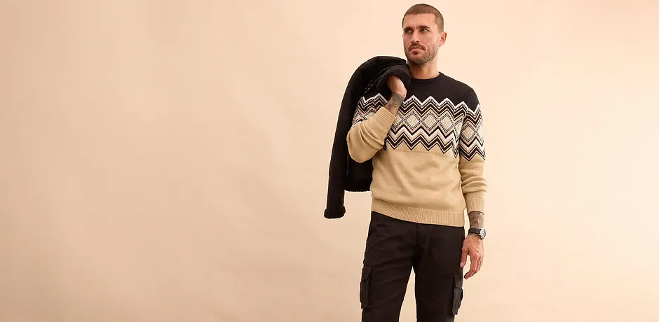 Stijlvolle look: zwarte winterjas, trui met print en jeans voor koude dagen.