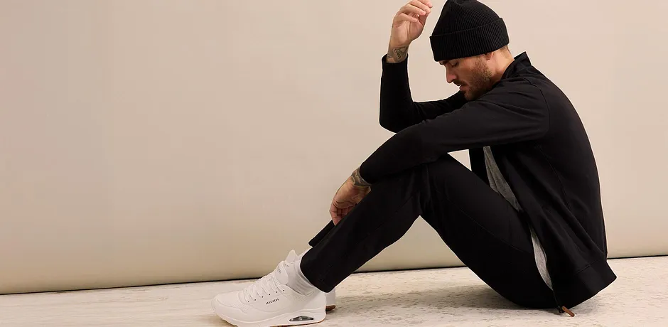 Zwart joggingpak met muts en witte sneakers.