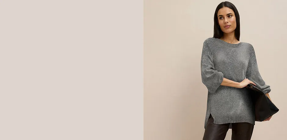 Grijze lange trui gecombineerd met donkere broek.