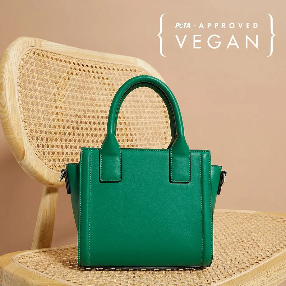 Een kleine groene handtas van vegan leer staat op een geweven stoel.