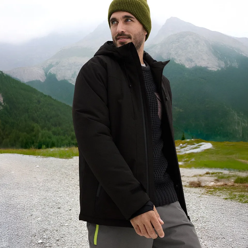 Zwarte jas en groene muts voor de perfecte winterlook.