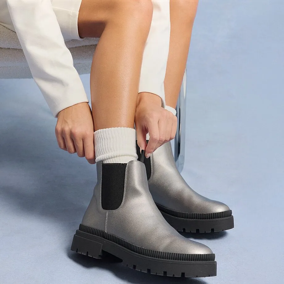 Witte sokken en zilveren Chelsea boots vormen een mooi contrast met de cr&egrave;mekleurige jurk.