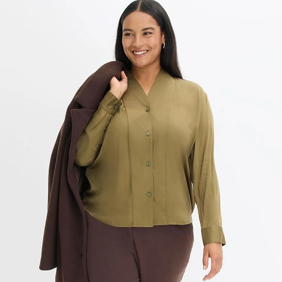 Combinatie van olijfgroene blouse en lange bruine jas.