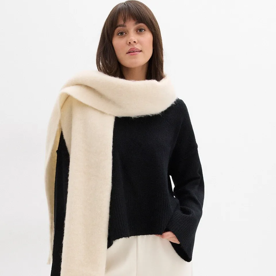 Zwarte trui gecombineerd met crèmekleurige sjaal.