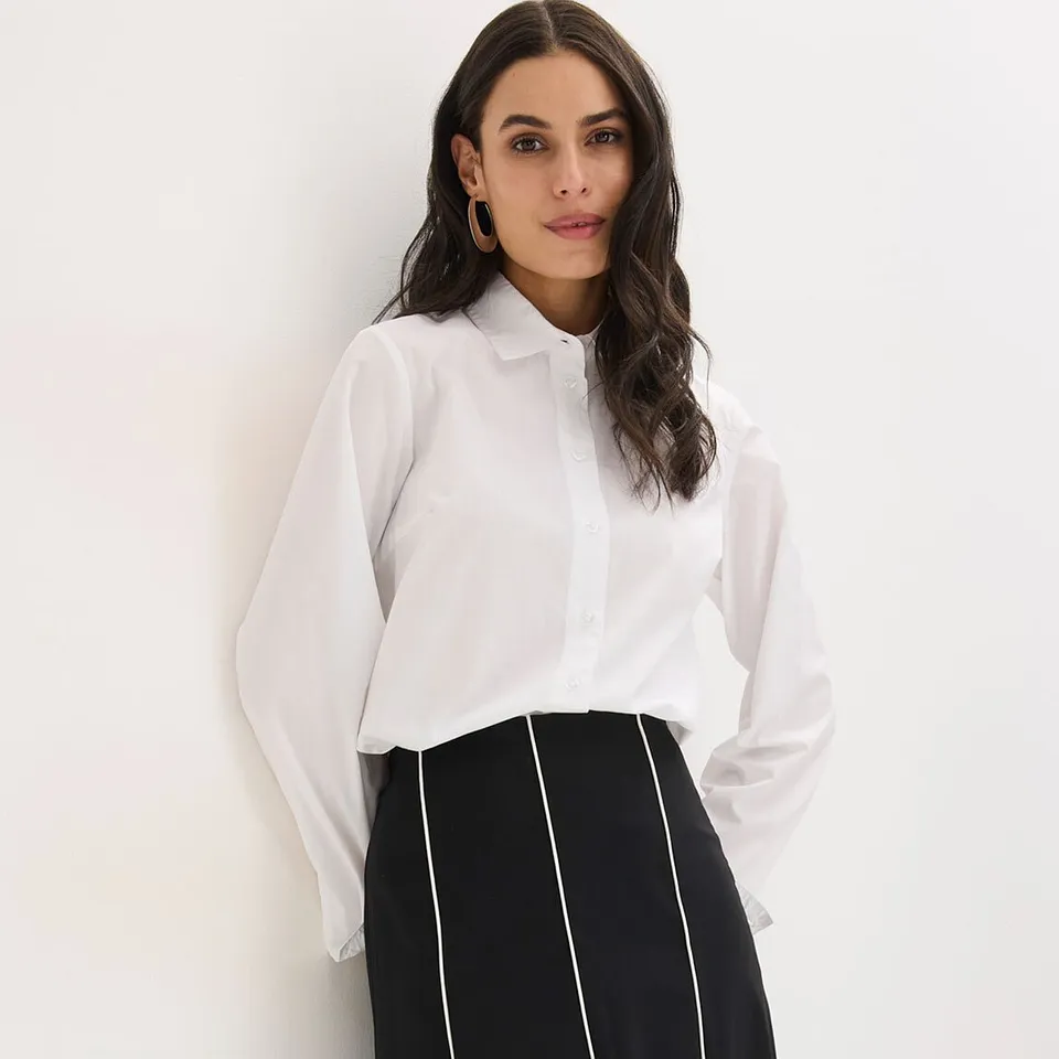 Witte overhemdblouse met kraag en zwart-witte rok met verticale strepen.