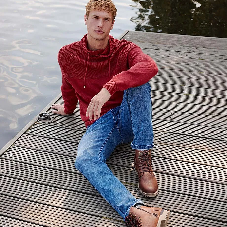 Rode trui met opstaande kraag gecombineerd met blauwe jeans en bruine leren boots.