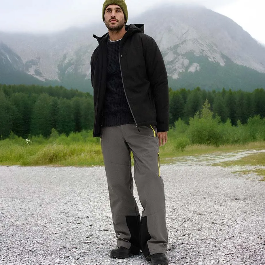 Donkere winterjas, grijze broek en groene muts.