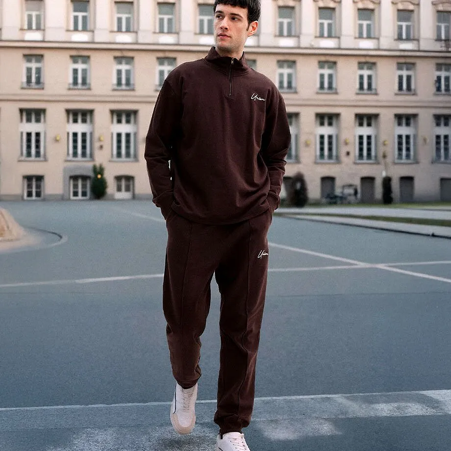 Donker joggingpak met witte sneakers eronder.