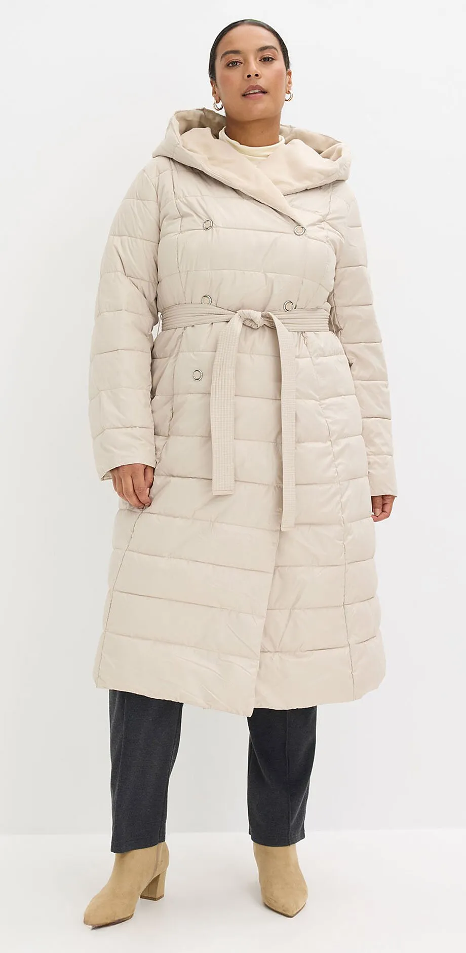 Cr&egrave;mekleurige gewatteerde lange jas met capuchon en ceintuur.