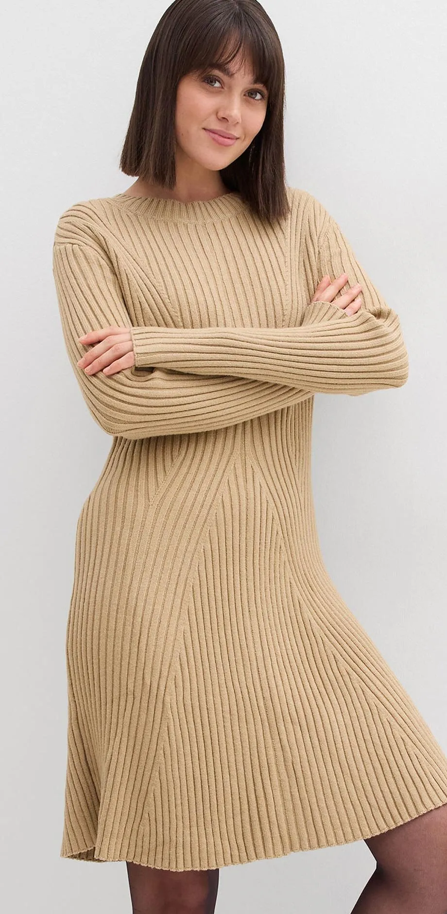 Beige gebreide jurk met geribd motief, lange mouwen en licht uitlopend rokgedeelte.