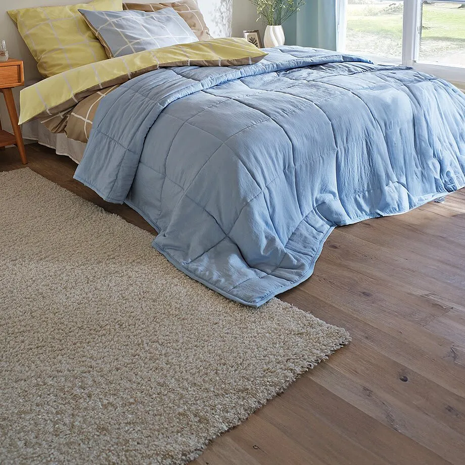 Beige vloerkleed ligt naast het bed.