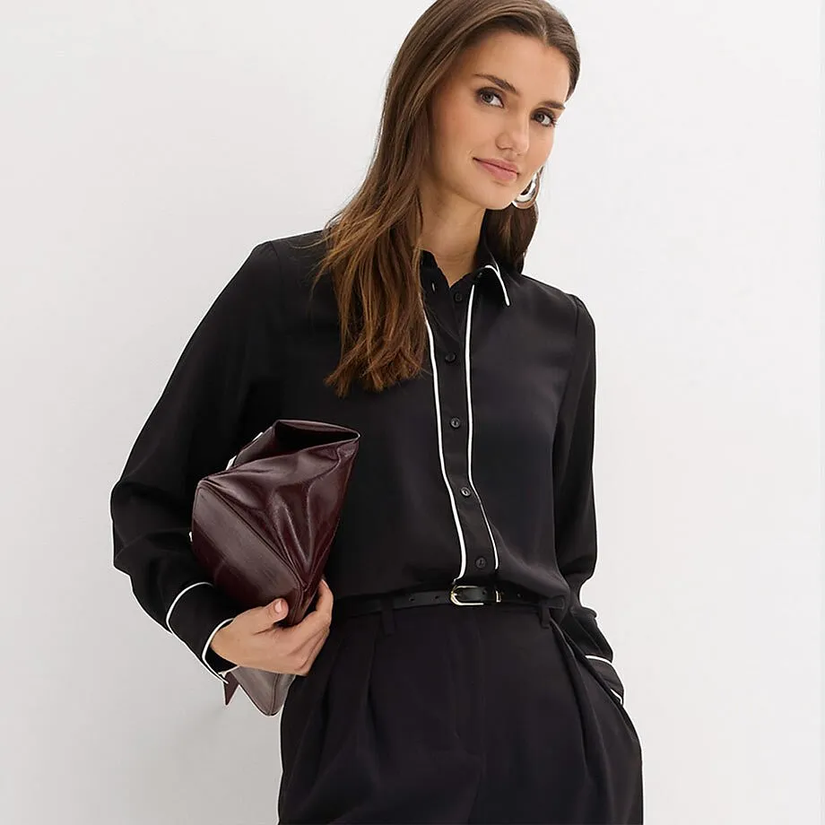 Zwarte overhemdblouse met witte kraag, gecombineerd met zwarte broek.